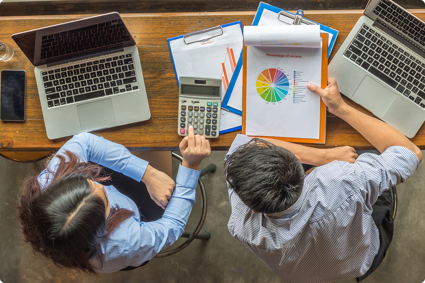 portrait-of-asian-successful-financier-worki-2025-03-25-09-21-04-utc 1 perennial accounting;man and woman sitting at a desk working with laptops and documents