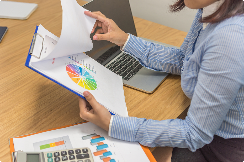 perennial accounting;woman sitting at a desk reading document at a desk with a laptop and calculator